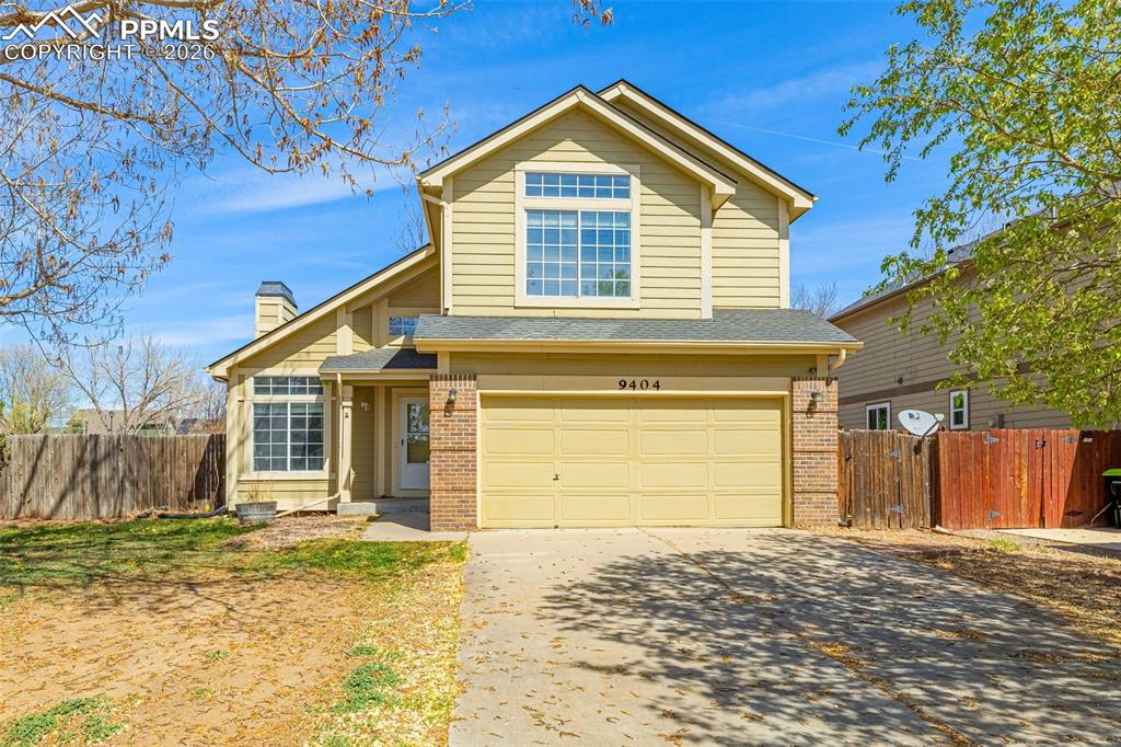 Image 1 of 28: Traditional home featuring a garage, brick siding, driveway, a chimney, and