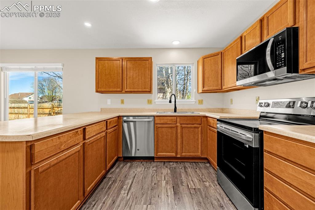 Image 10 of 28: Kitchen featuring stainless steel appliances, light countertops, wood finis
