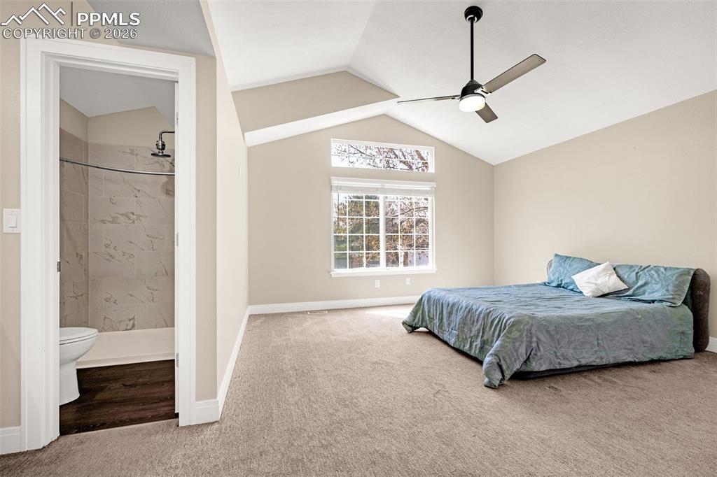 Image 19 of 28: Carpeted bedroom with connected bathroom and a ceiling fan
