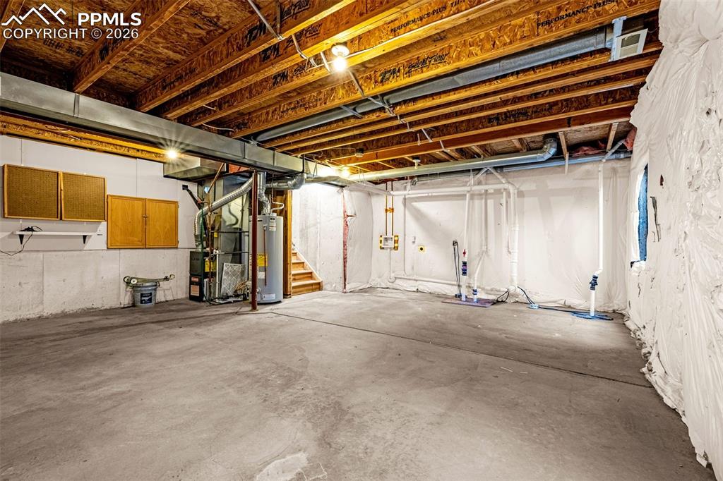 Image 25 of 28: Unfinished basement featuring water heater and heating unit