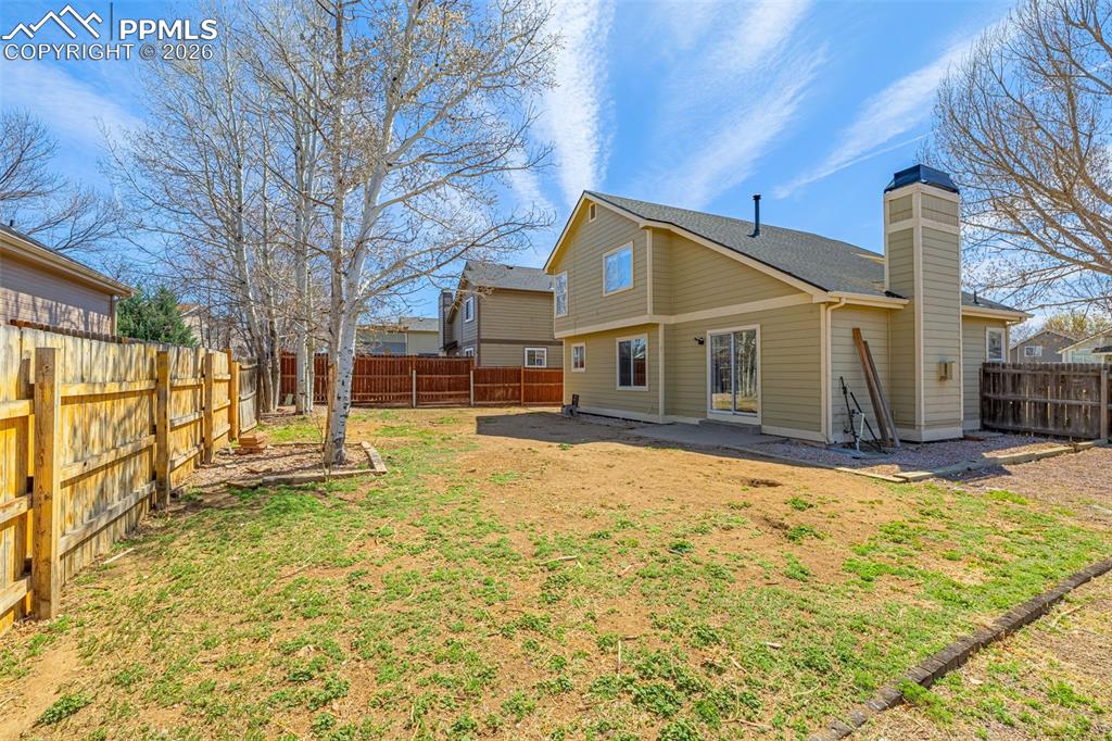 Image 26 of 28: Rear view of house with a chimney and a fenced backyard