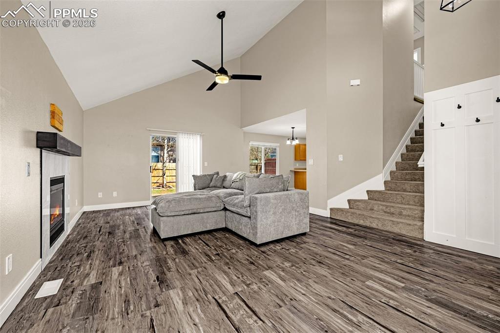 Image 4 of 28: Living area with a fireplace, dark wood-type flooring, lofted ceiling, and