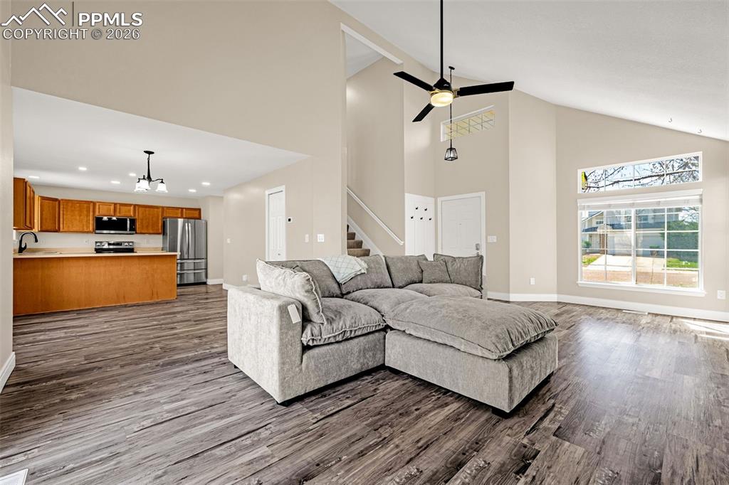 Image 5 of 28: Living room with a high ceiling, a chandelier, dark wood-style flooring, an