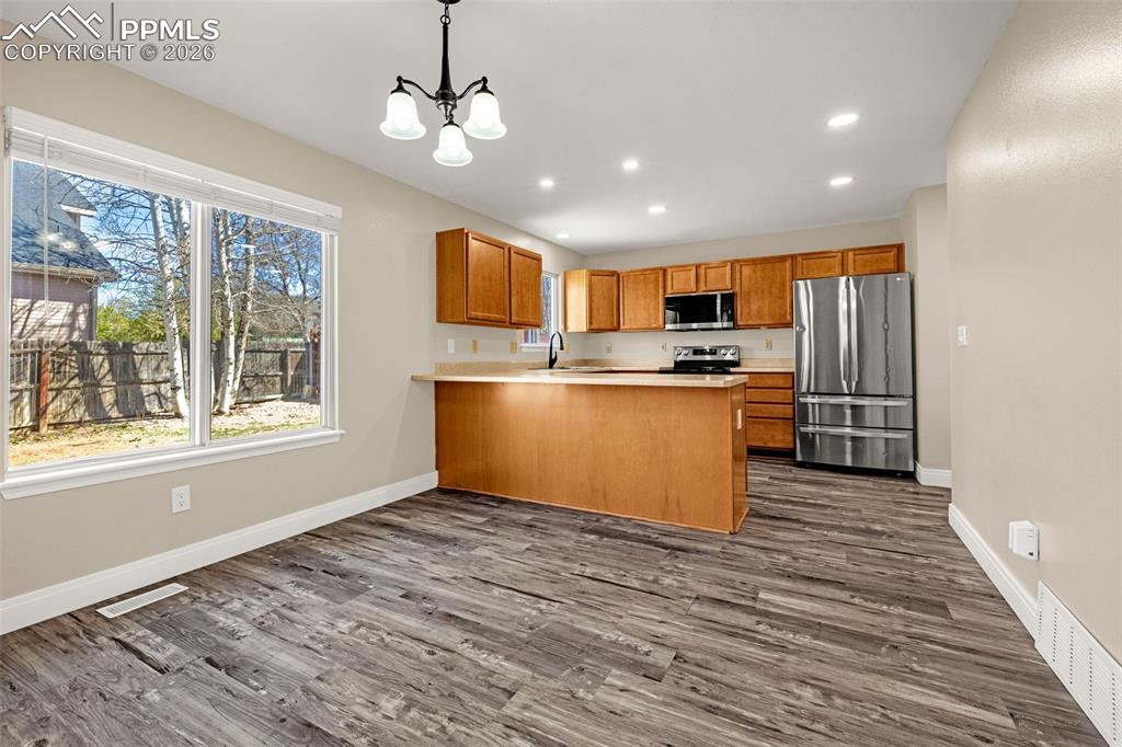Image 8 of 28: Kitchen with light countertops, a peninsula, stainless steel appliances, an