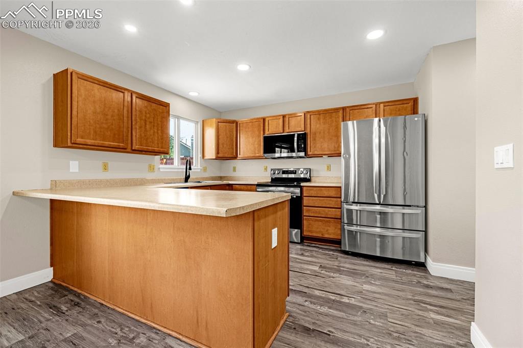 Image 9 of 28: Kitchen featuring stainless steel appliances, a peninsula, light countertop