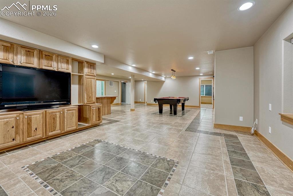 Image 31 of 50: Basement Family Recreation Room with game area and wet bar/kitchenette.
