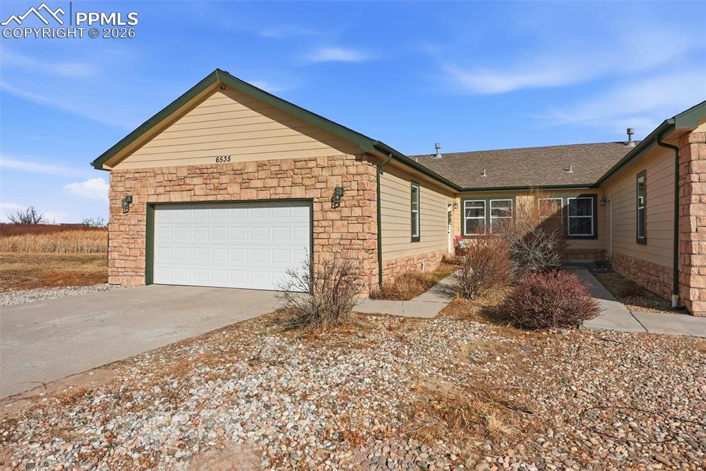 Image 1 of 41: View of property exterior with stone siding, a garage, and driveway
