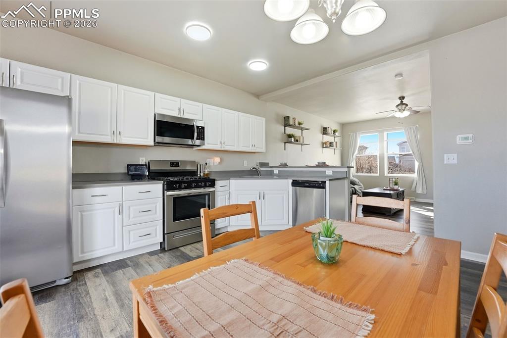 Image 13 of 41: Kitchen featuring stainless steel appliances, white cabinets, light wood fi
