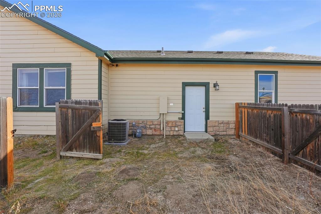 Image 31 of 41: Back of property with a gate, stone siding, and a shingled roof