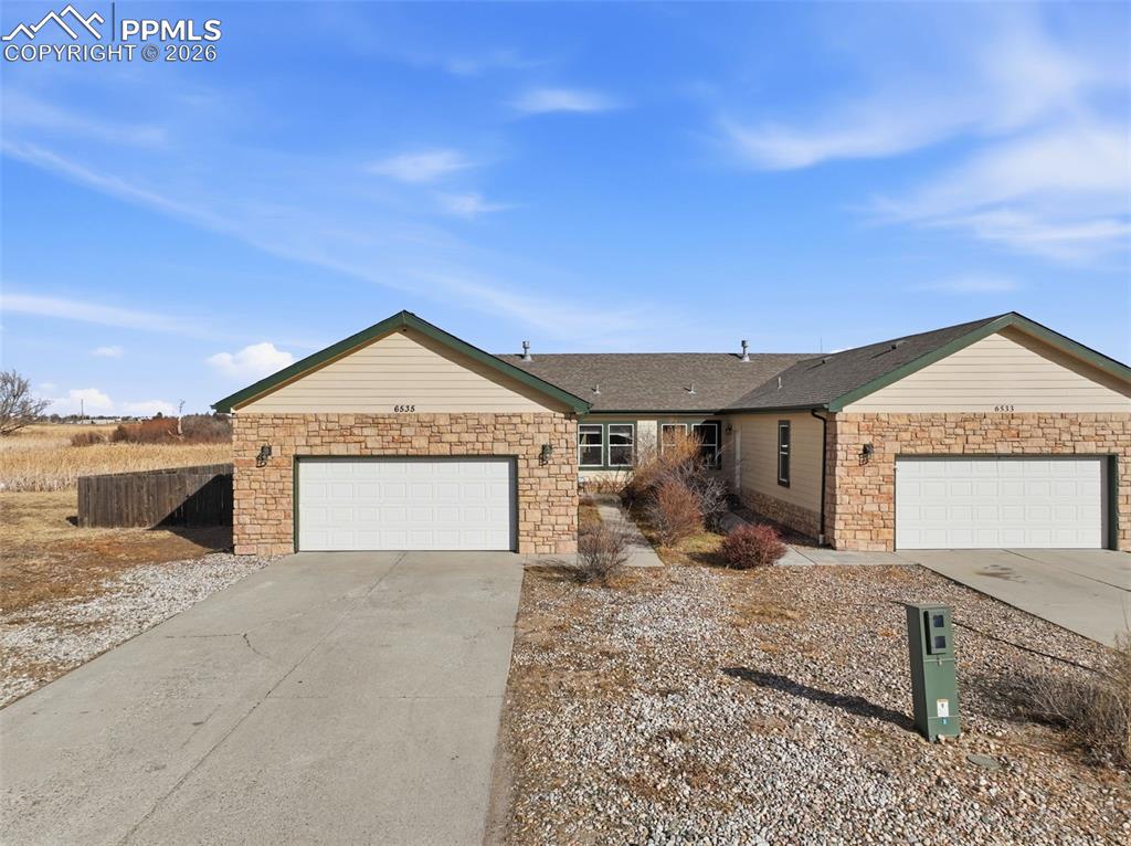 Image 33 of 41: Single story home featuring stone siding, driveway, an attached garage, and