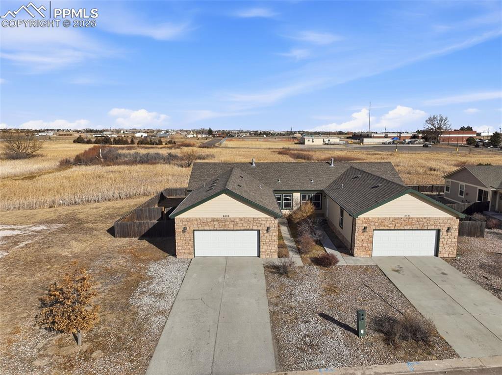 Image 35 of 41: Ranch-style house with stone siding, an attached garage, and driveway
