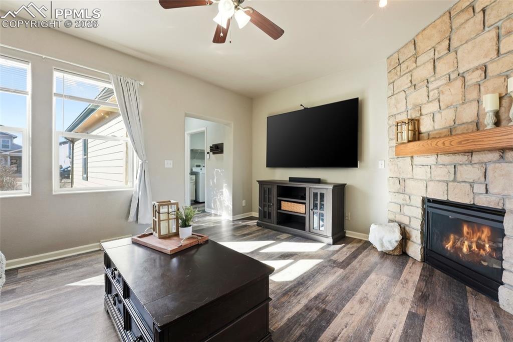 Image 6 of 41: Living room featuring a fireplace, ceiling fan, dark wood-type flooring, an