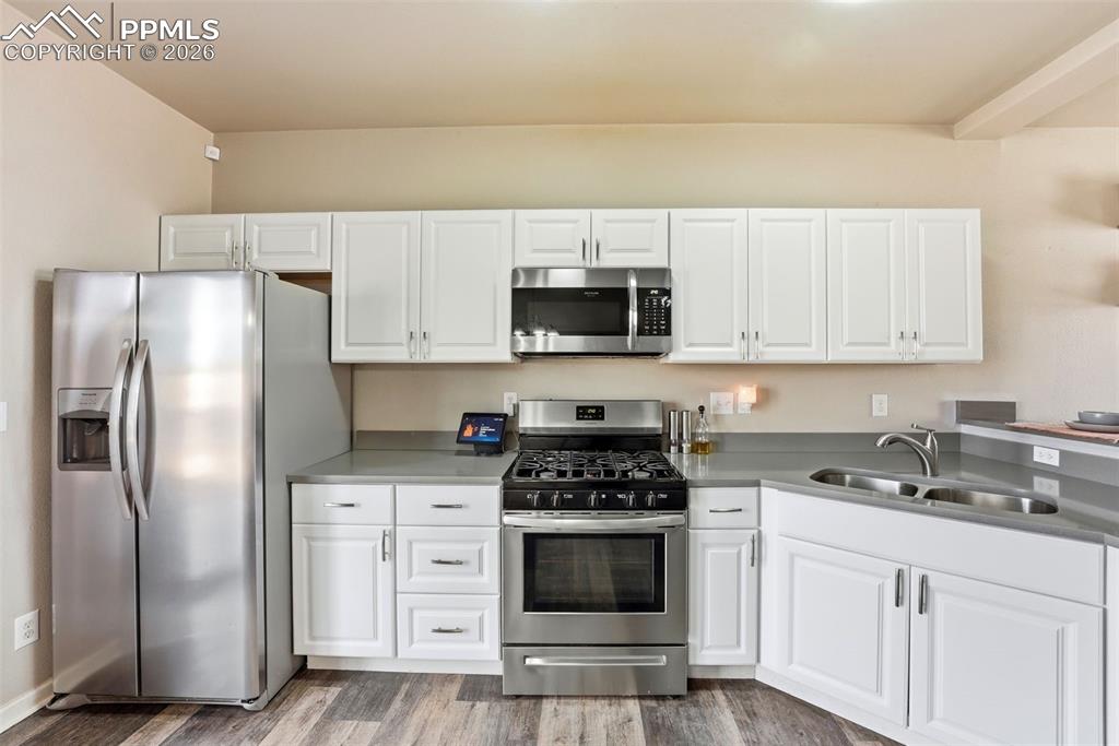 Image 9 of 41: Kitchen featuring stainless steel appliances, white cabinets, and light woo