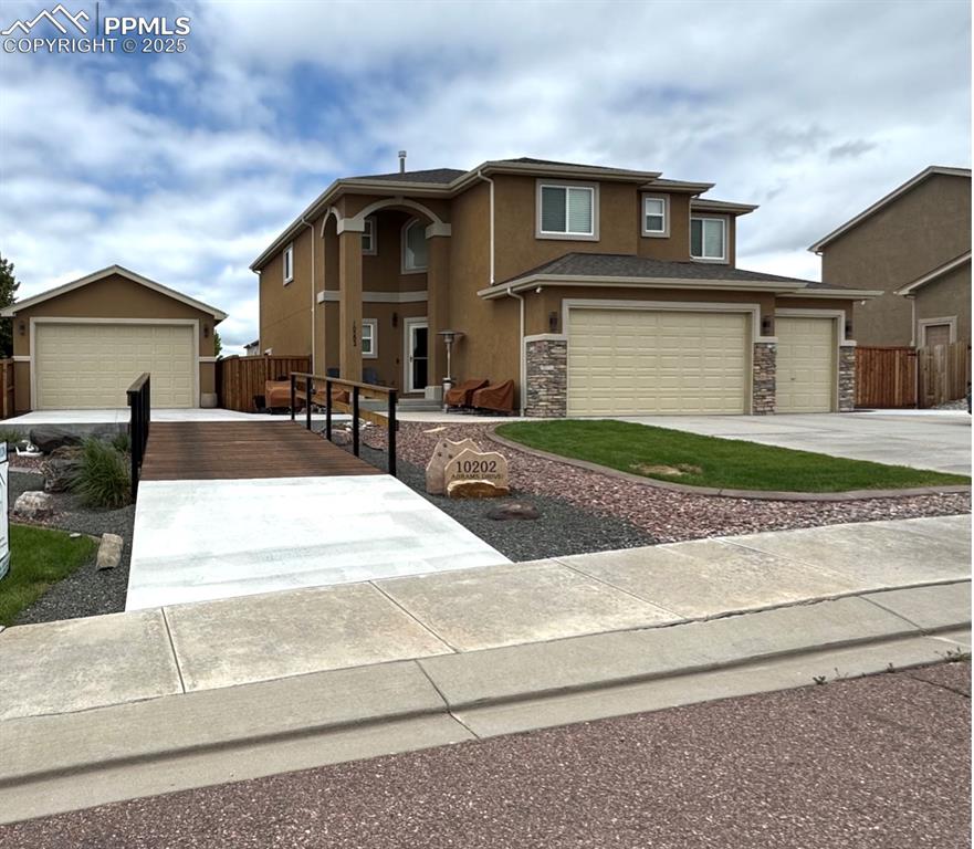 Caption: View of front facade featuring stucco siding, stone siding, and driveway