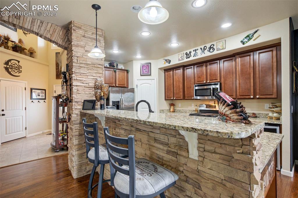 Image 12 of 49: Kitchen featuring appliances with stainless steel finishes, a breakfast bar