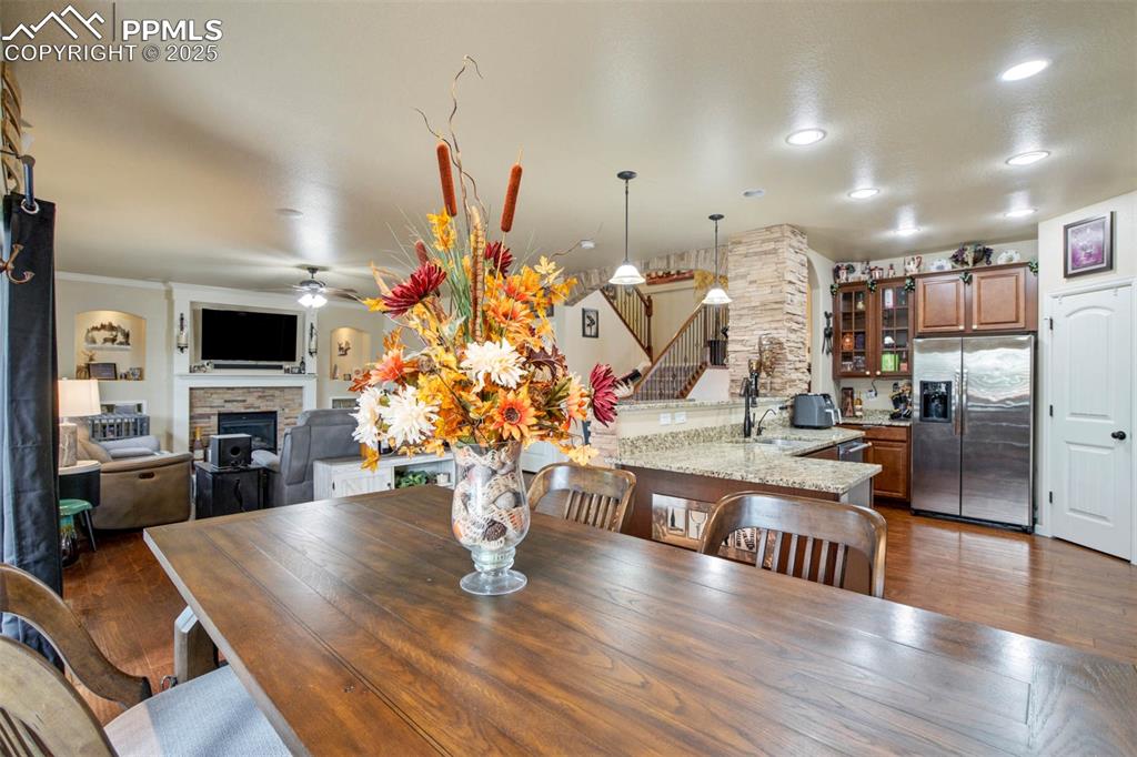 Image 13 of 49: Dining room featuring stairway, a fireplace, ceiling fan, dark wood-style f
