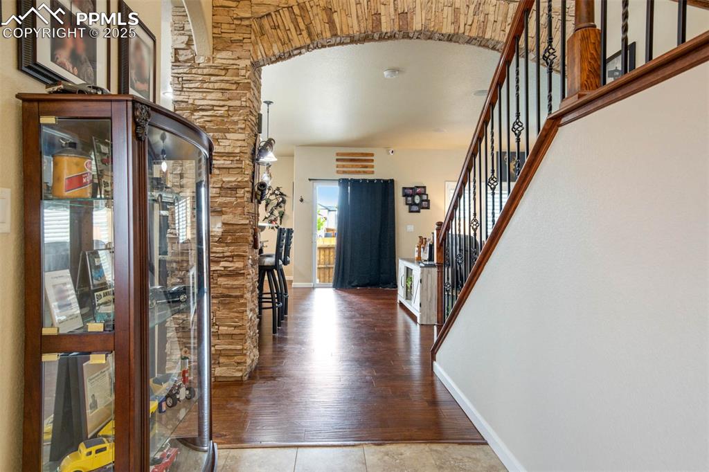 Image 17 of 49: Entryway featuring arched walkways, stairs, and wood finished floors