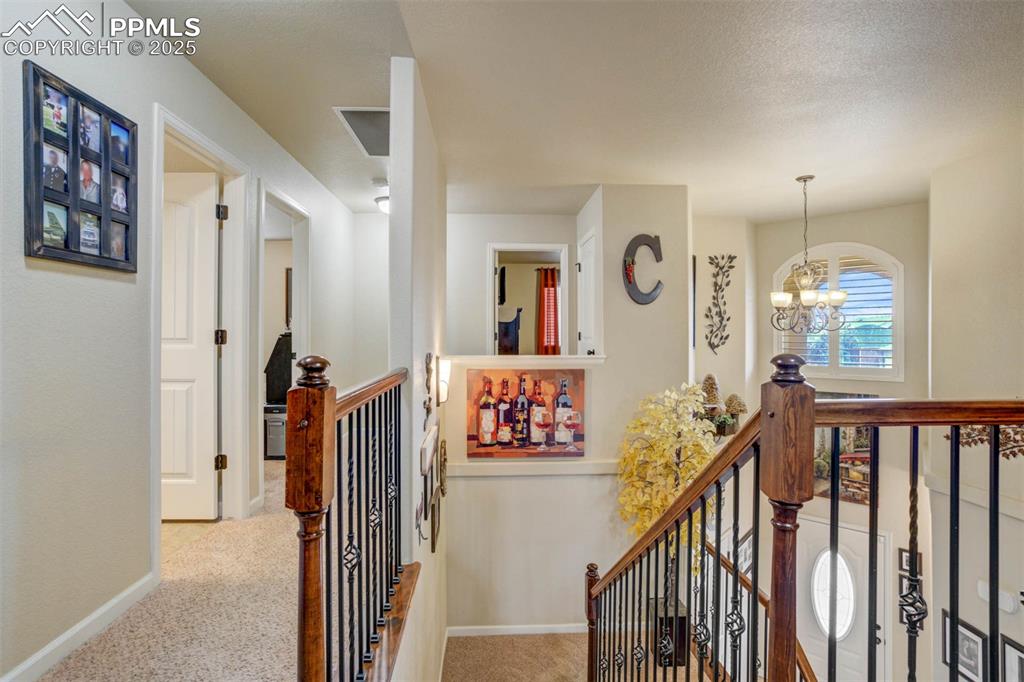 Image 20 of 49: Corridor featuring an upstairs landing, a chandelier, and carpet floors