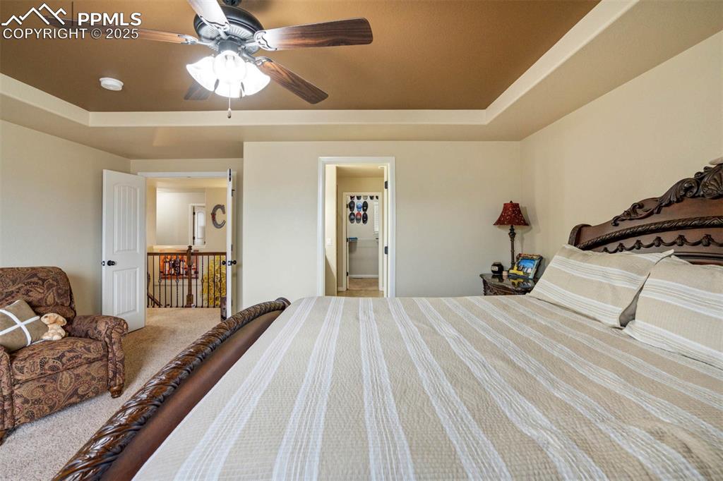 Image 22 of 49: Carpeted bedroom featuring a raised ceiling and ceiling fan