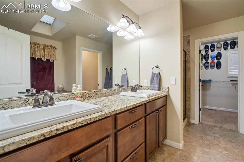Image 23 of 49: Bathroom with a skylight, double vanity, and a shower stall