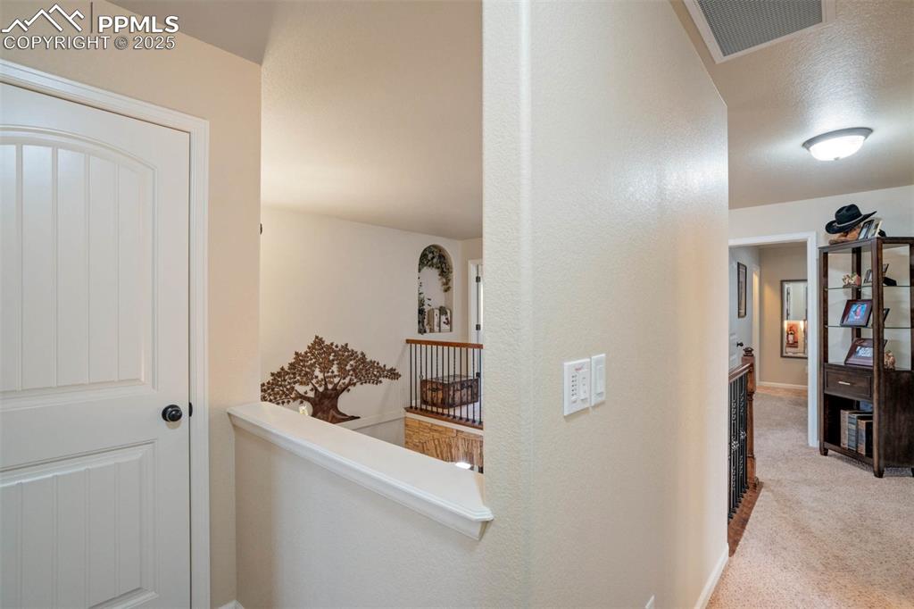 Image 29 of 49: Hall featuring an upstairs landing and carpet flooring