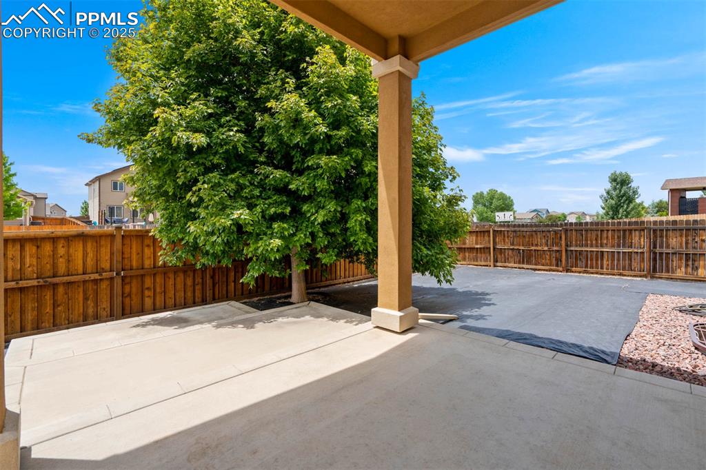 Image 46 of 49: Fenced backyard with a patio area