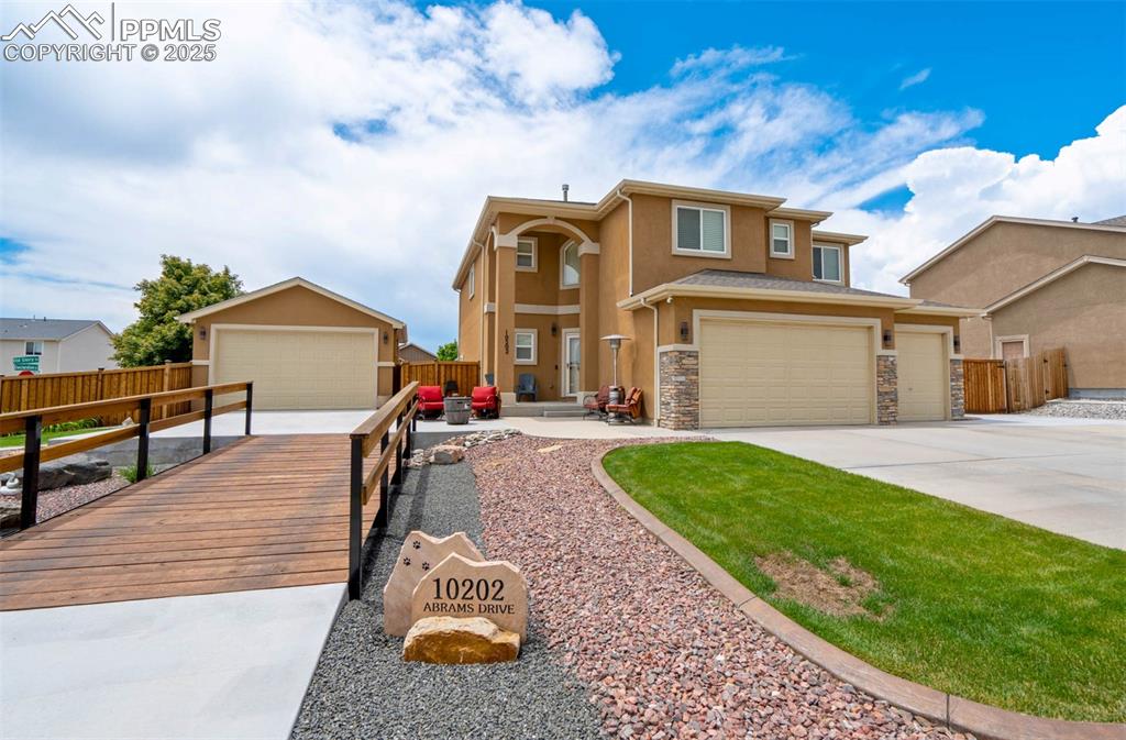 Image 7 of 49: View of front of home with stucco siding, stone siding, and concrete drivew