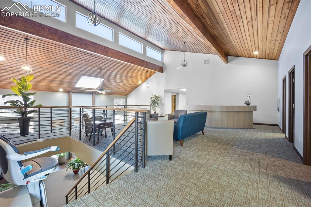 Image 18 of 50: Hallway with carpet floors, an upstairs landing, high vaulted ceiling, beam