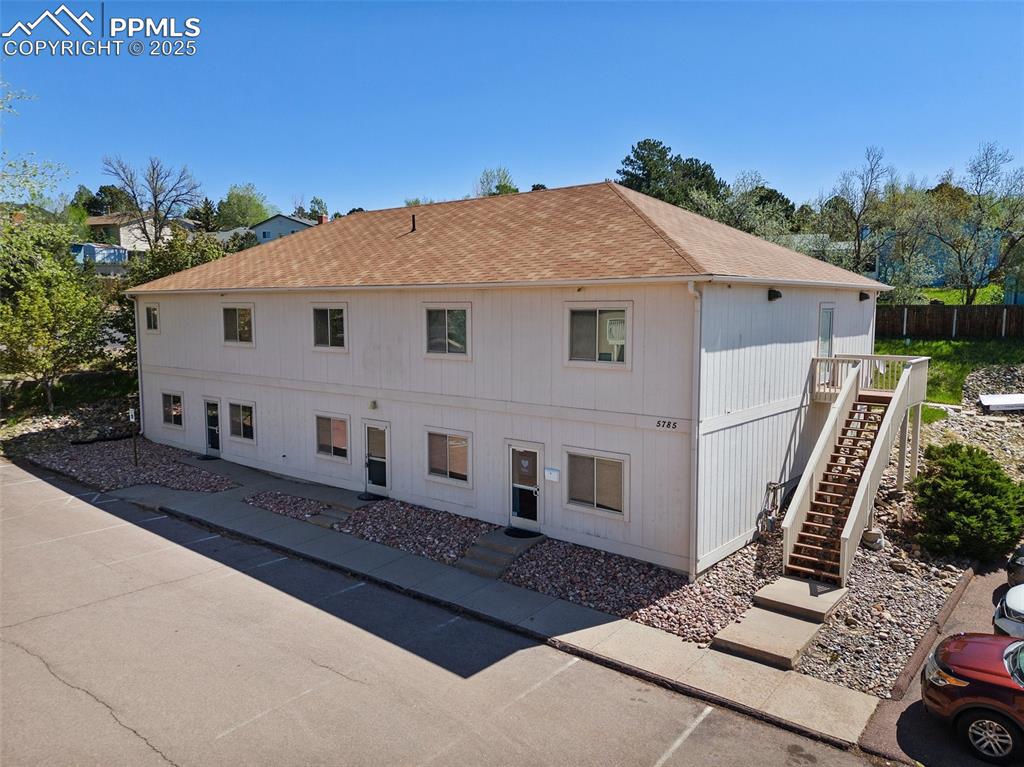 Image 2 of 50: Rear view of property with stairs, a shingled roof, and fence - 5785 Buildi