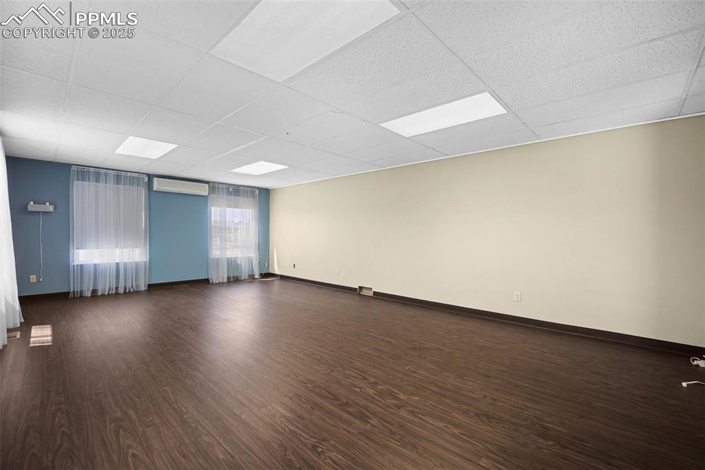 Image 23 of 50: Spare room featuring a paneled ceiling, dark wood finished floors, a wall m