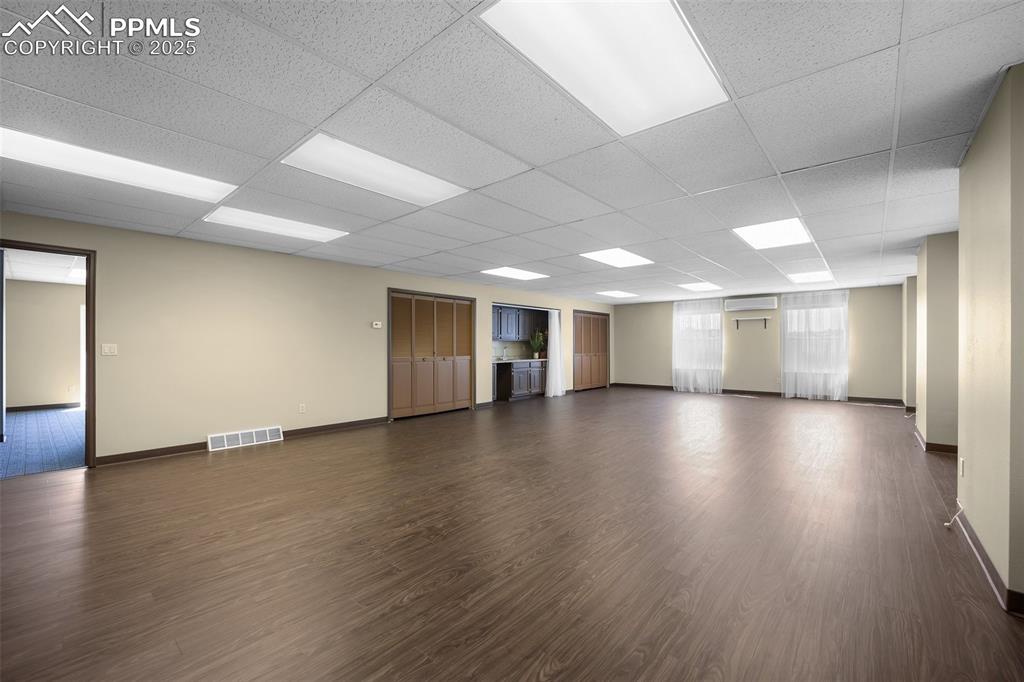 Image 24 of 50: Unfurnished room with baseboards, dark wood finished floors, a wall unit AC