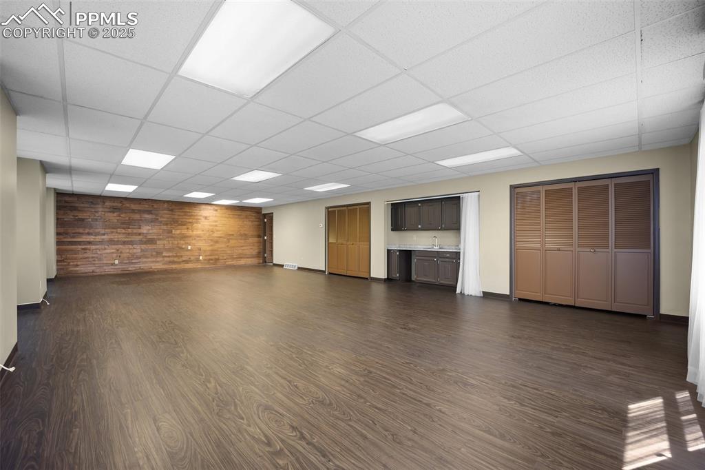 Image 25 of 50: Unfurnished living room featuring dark wood-style floors, a drop ceiling, w