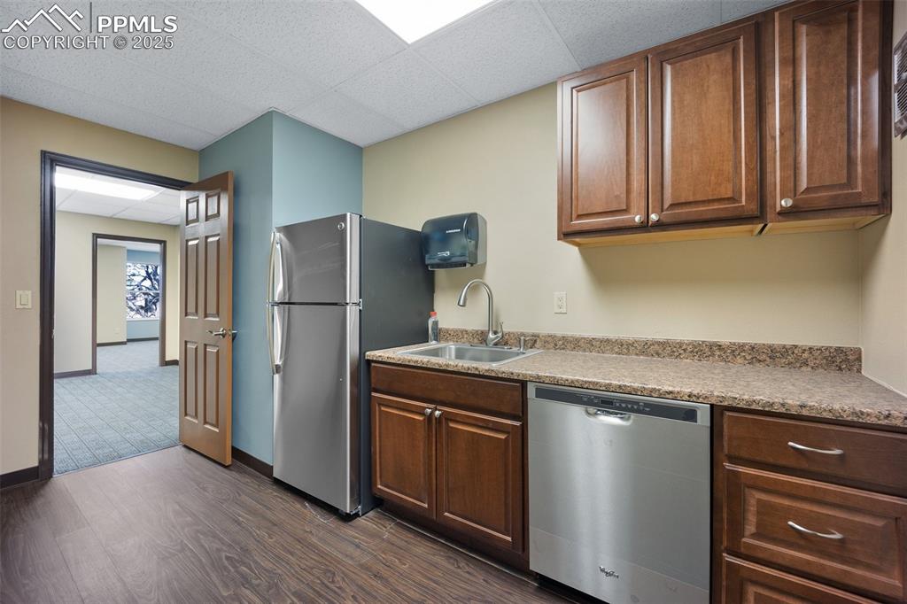 Image 27 of 50: Kitchen with appliances with stainless steel finishes, a sink, and dark woo