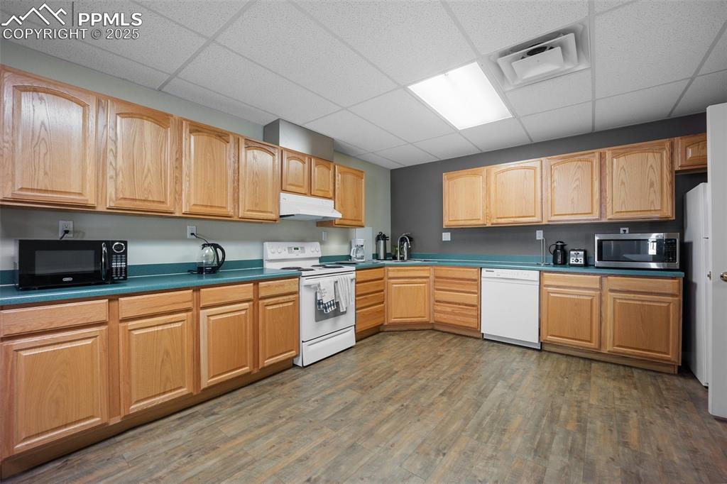 Image 35 of 50: Kitchen with white appliances, under cabinet range hood, a drop ceiling, wo