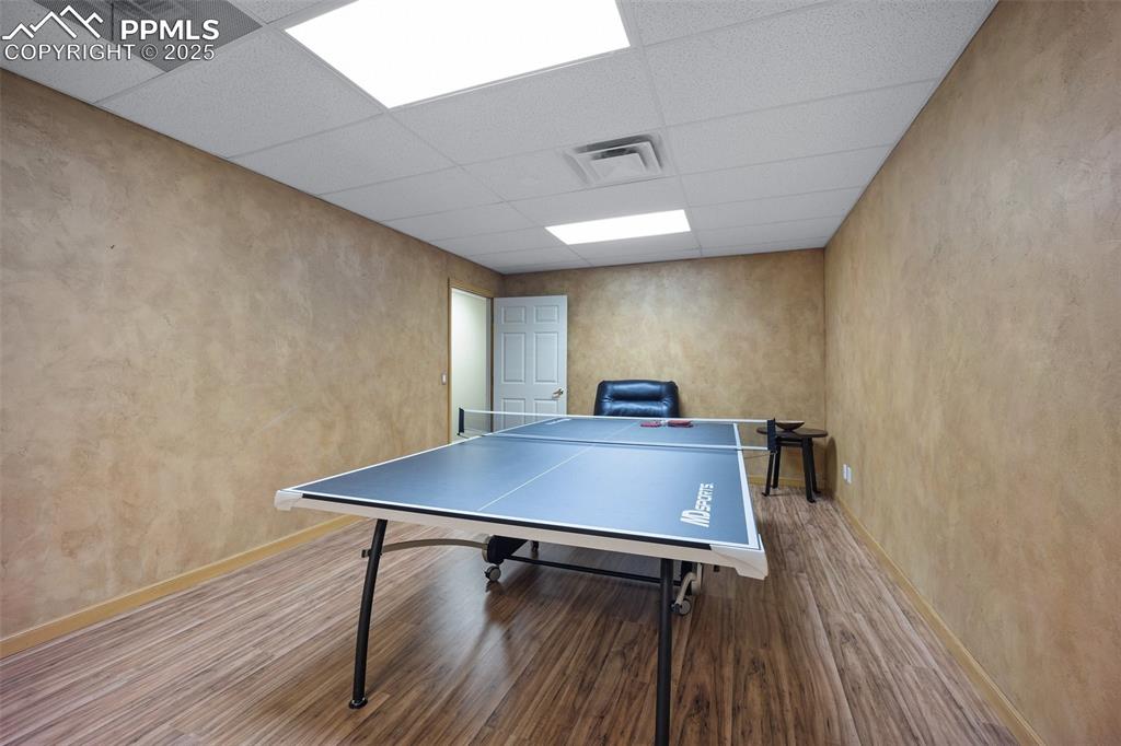 Image 37 of 50: Game room featuring a paneled ceiling, wood finished floors, and baseboards