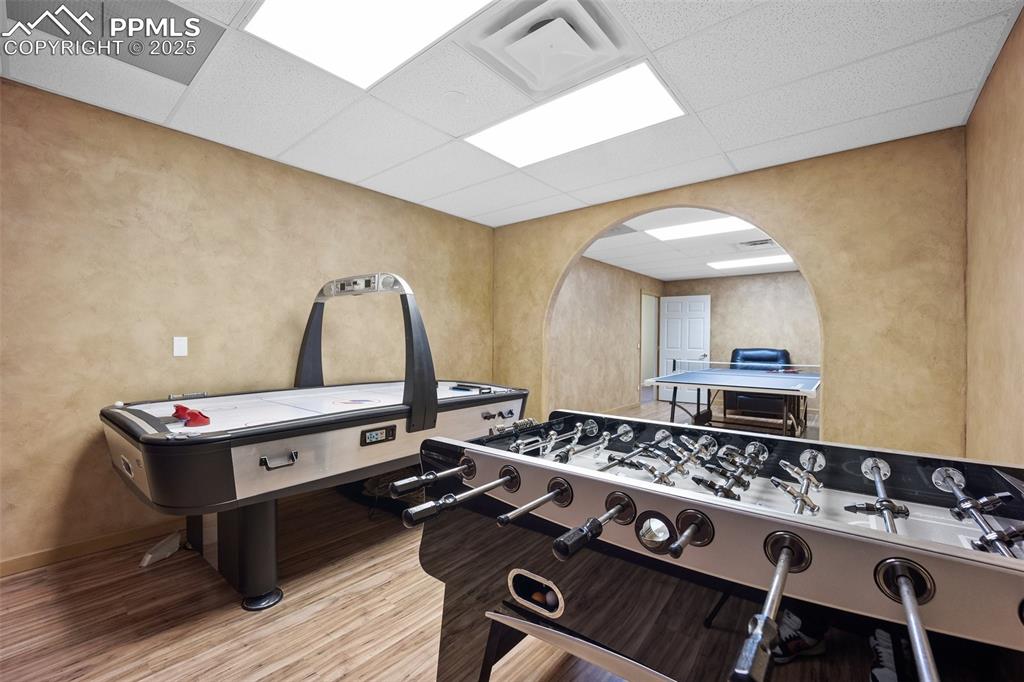 Image 38 of 50: Game room with arched walkways, wood finished floors, a paneled ceiling, a 