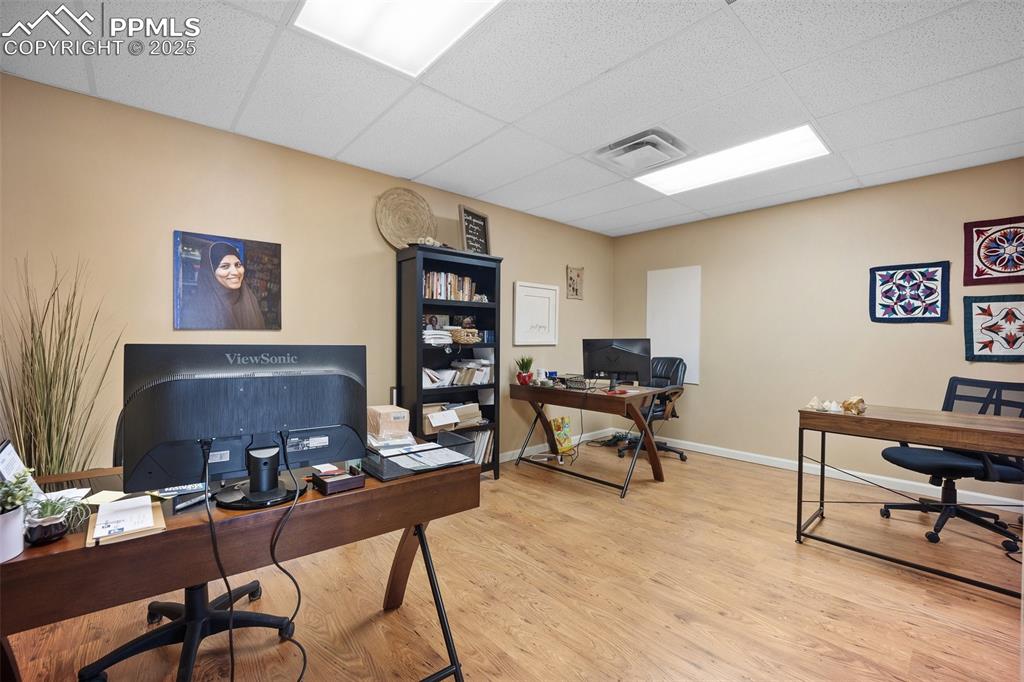 Image 45 of 50: Home office featuring a paneled ceiling, wood finished floors, and baseboar