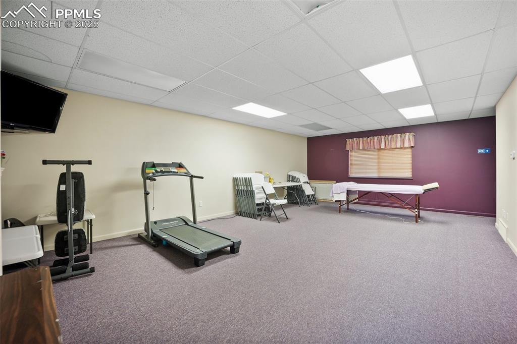 Image 46 of 50: Workout area with a paneled ceiling, baseboards, and carpet floors5785 Buil