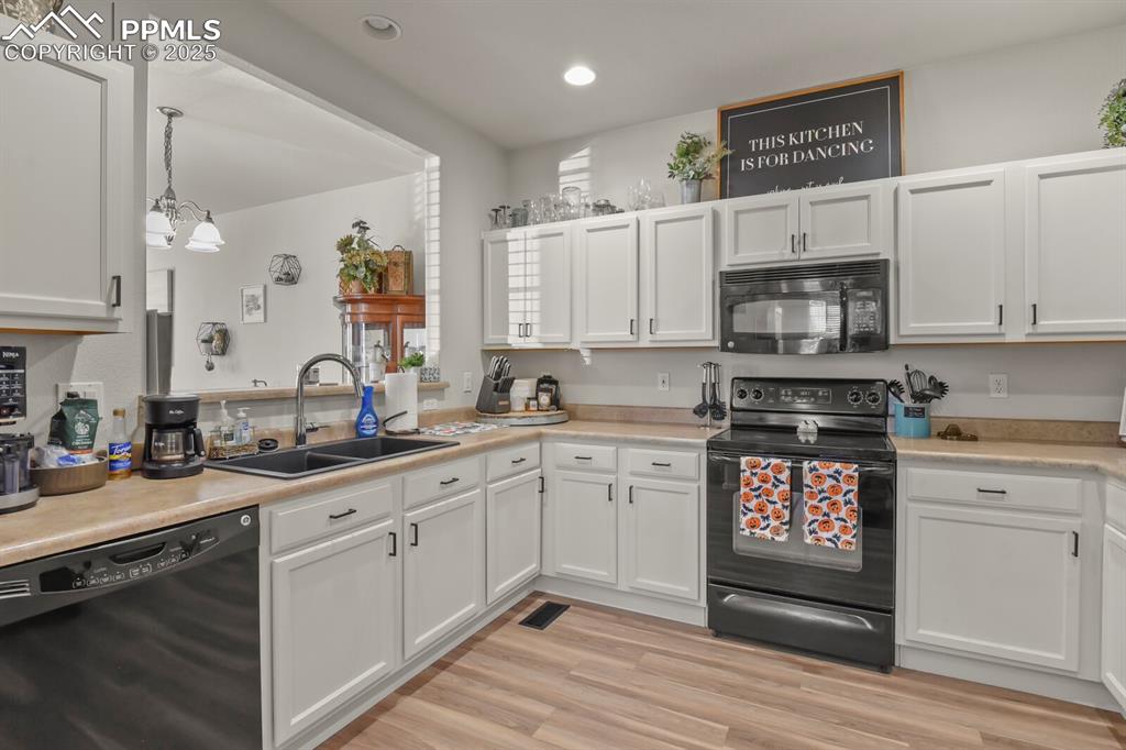 Image 10 of 27: Kitchen with black appliances, white cabinets, light countertops, and reces