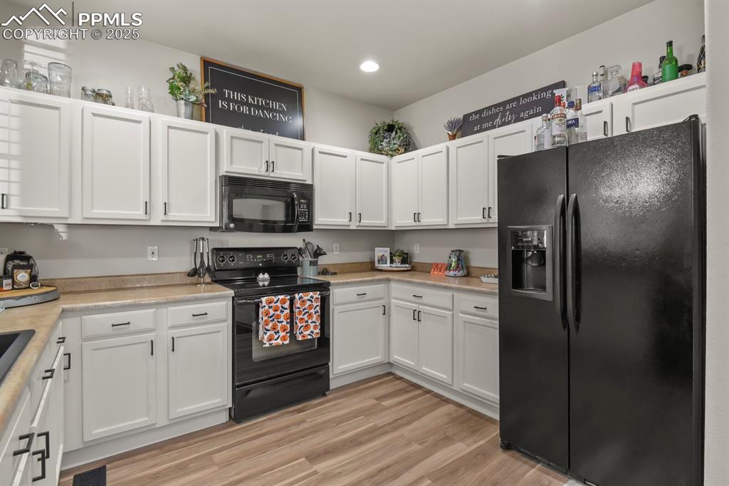 Image 11 of 27: Kitchen featuring black appliances, white cabinets, light countertops, ligh