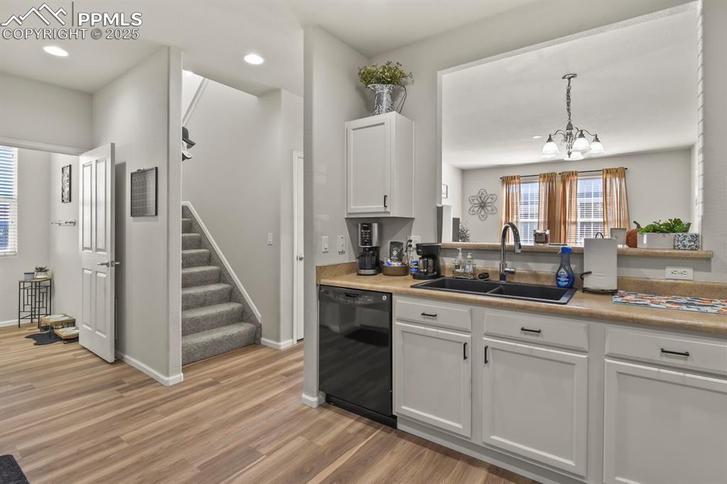 Image 12 of 27: Kitchen with white cabinets, black dishwasher, light wood-style floors, a c