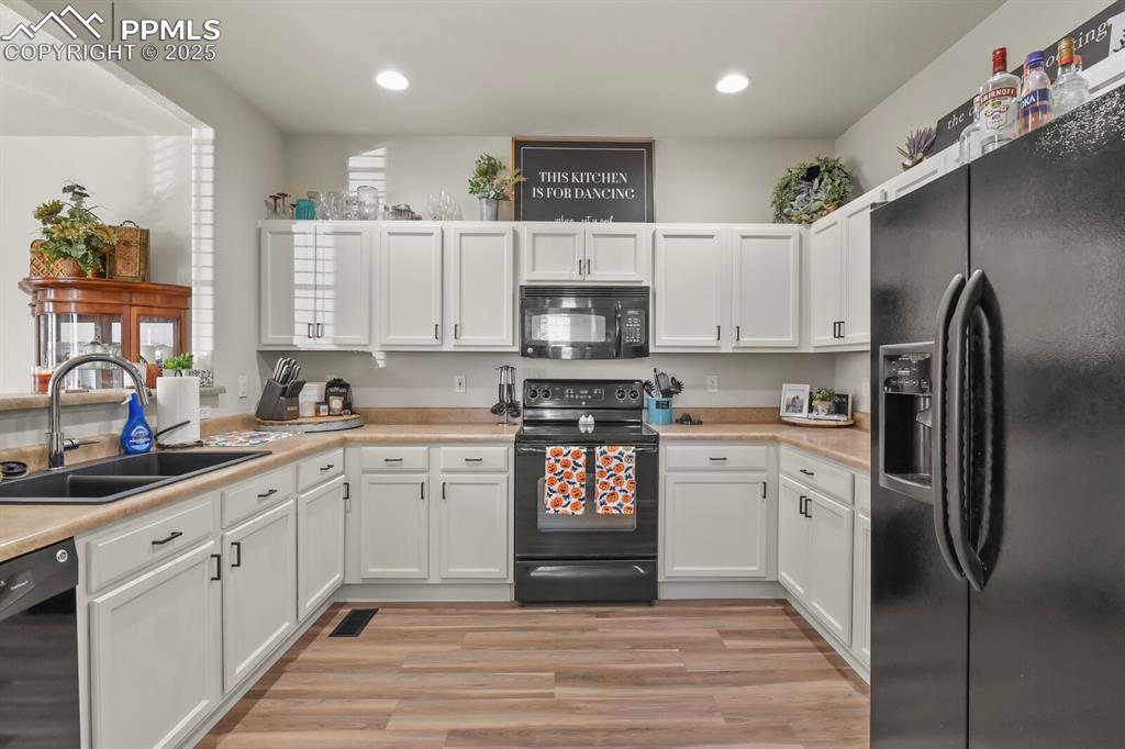 Image 13 of 27: Kitchen featuring black appliances, white cabinets, light countertops, ligh