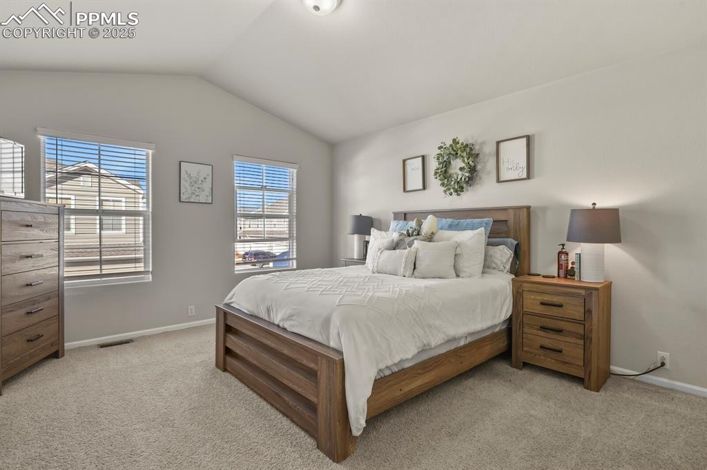 Image 15 of 27: Bedroom with lofted ceiling and light carpet