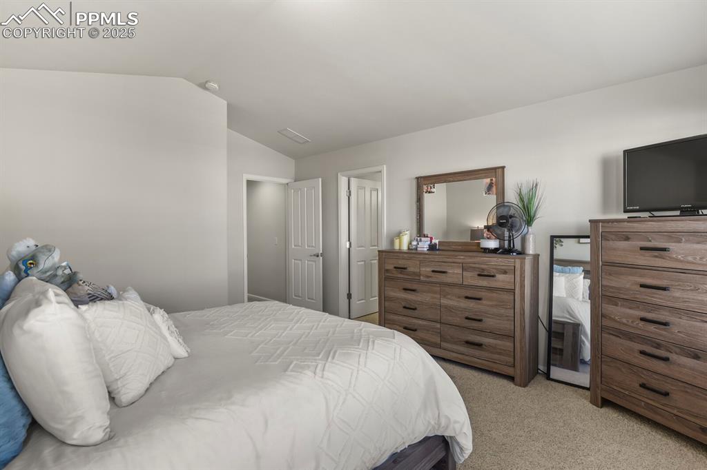 Image 16 of 27: Bedroom with light colored carpet and lofted ceiling