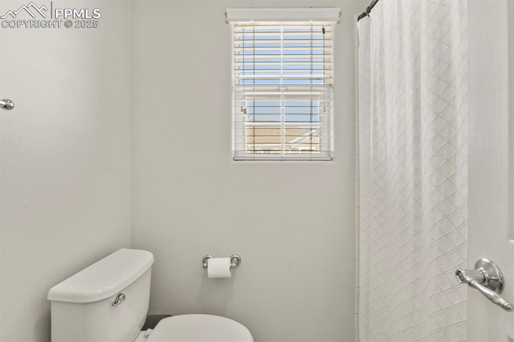 Image 21 of 27: Bathroom featuring toilet and a shower with curtain