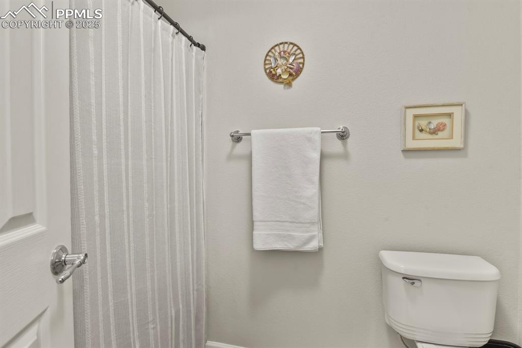 Image 22 of 27: Bathroom with a shower with curtain and toilet