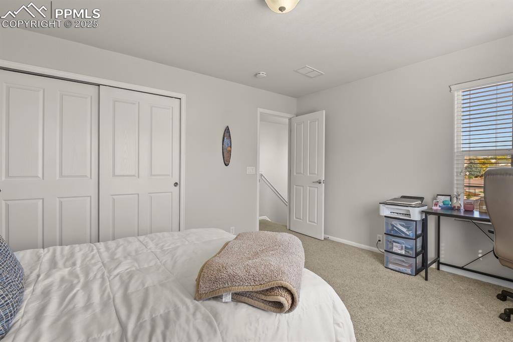 Image 23 of 27: Bedroom with light carpet, a closet, and an office area