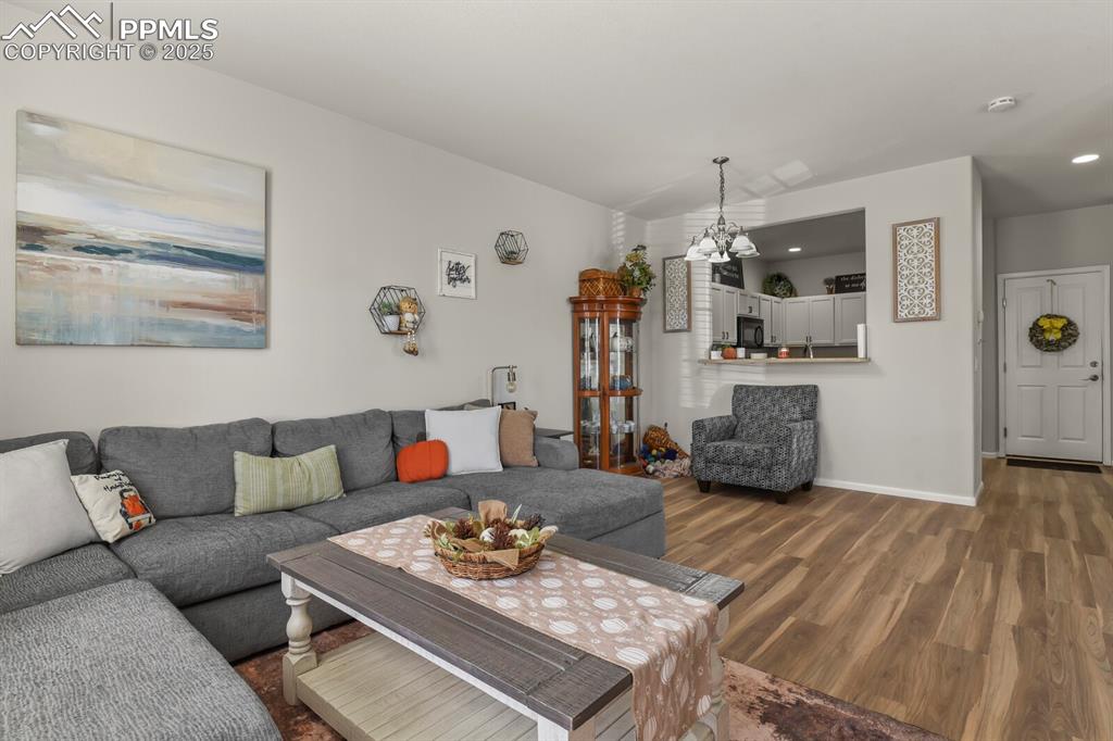 Image 6 of 27: Living room with dark wood-style floors, recessed lighting, and a chandelie