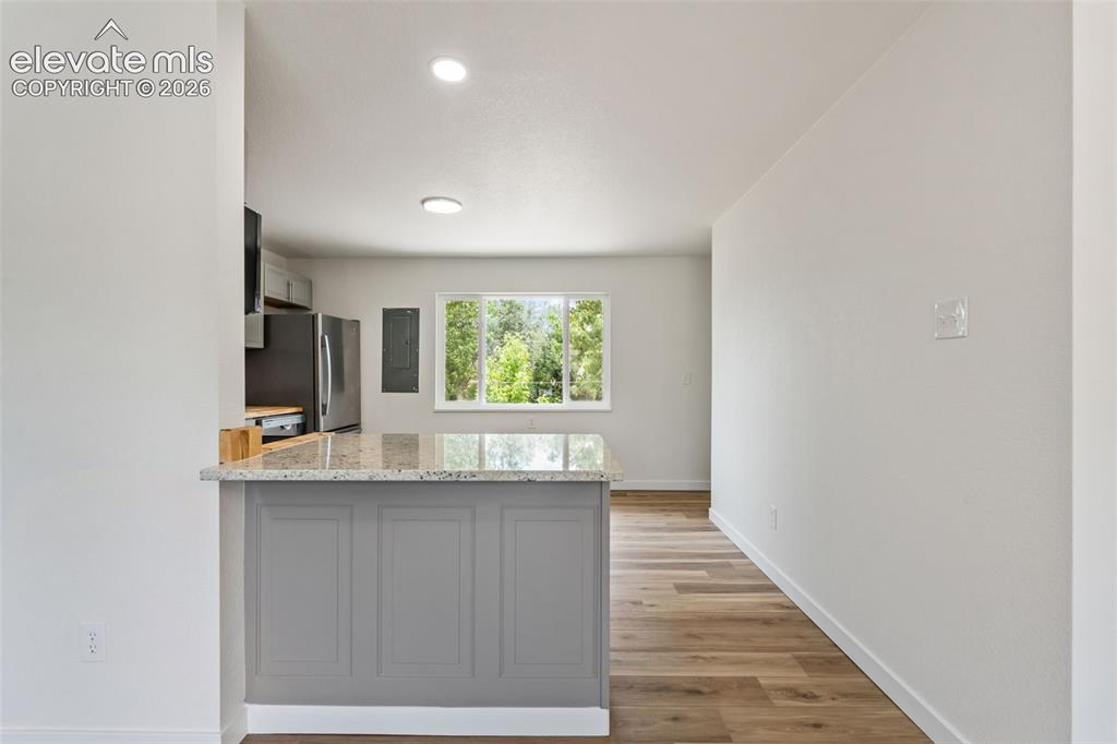 Image 11 of 35: Kitchen island with a granite-style countertop and gray paneling