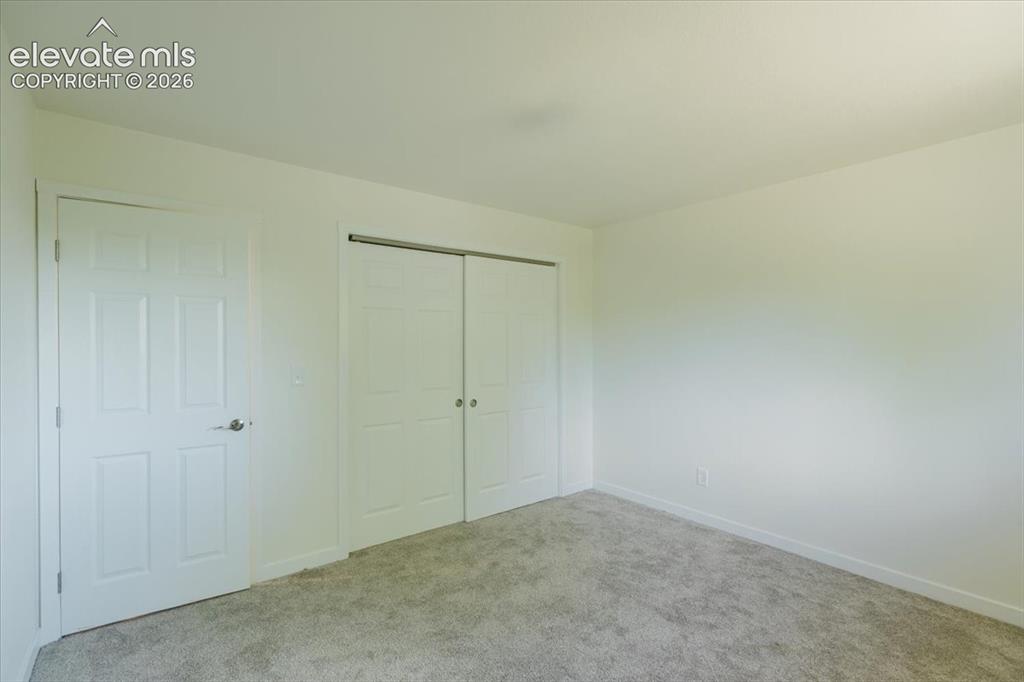 Image 12 of 27: Interior room featuring neutral wall paint, light gray carpeting, and white